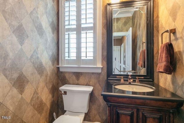 bathroom with vanity, toilet, and tile walls