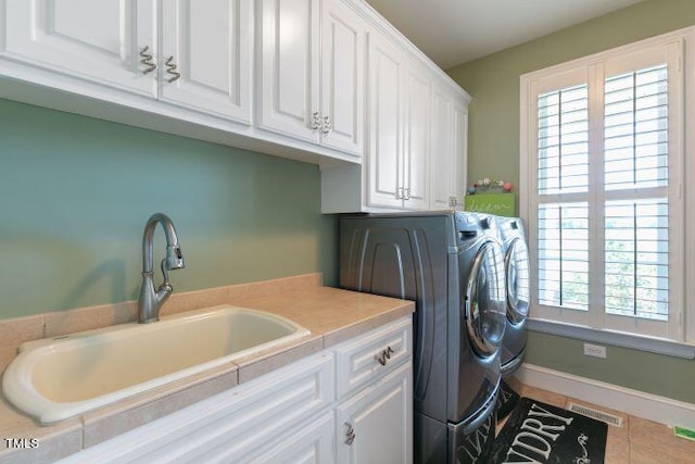 laundry area featuring sink, light tile patterned flooring, independent washer and dryer, and cabinets