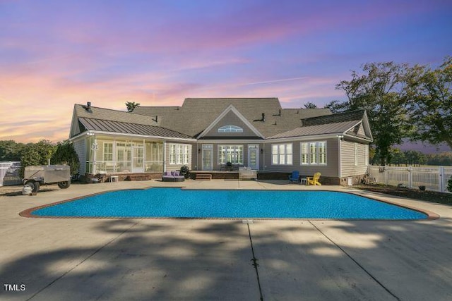 back house at dusk with a patio and a fenced in pool