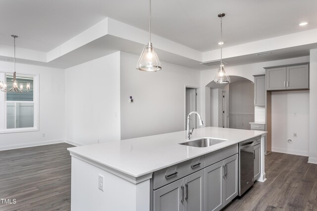 kitchen featuring pendant lighting, a center island with sink, gray cabinetry, and sink