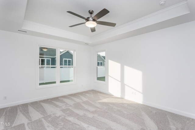 carpeted empty room featuring a tray ceiling, ceiling fan, and ornamental molding