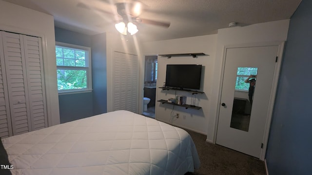 bedroom with dark carpet, a ceiling fan, and multiple closets