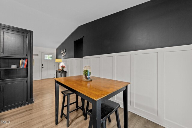6125 Bellow St, Raleigh, NC 27609 - dining room featuring a decorative wall, light wood finished floors, a wainscoted wall, and vaulted ceiling