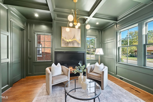 sitting room featuring beam ceiling, coffered ceiling, light hardwood / wood-style floors, a chandelier, and ornamental molding