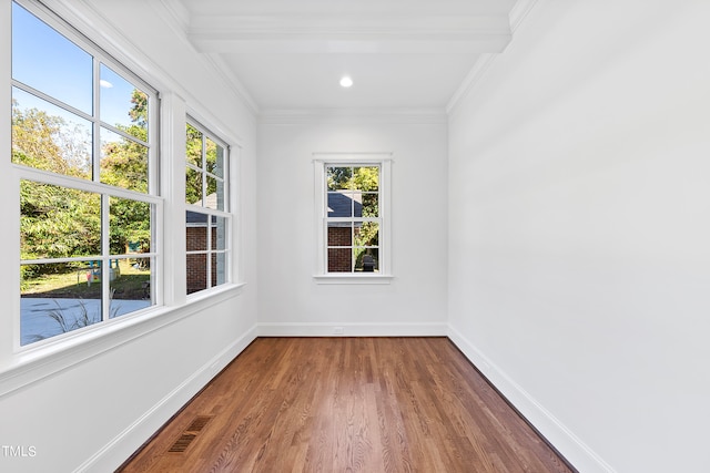 spare room with hardwood / wood-style flooring, beam ceiling, and crown molding