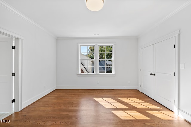 unfurnished bedroom with light wood-type flooring, a closet, and crown molding