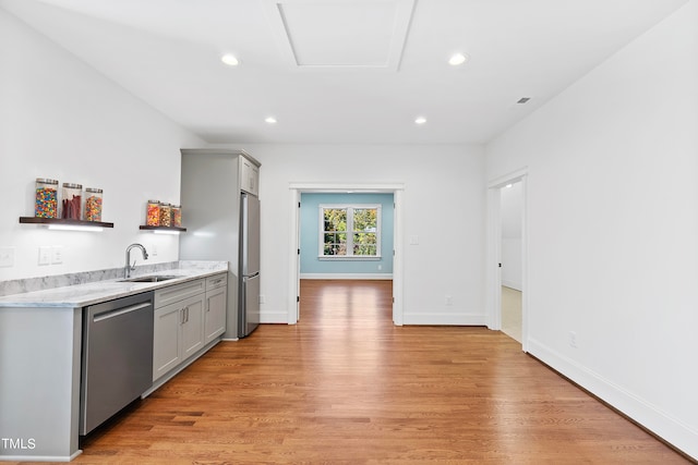 kitchen with stainless steel appliances, gray cabinets, light hardwood / wood-style floors, and sink