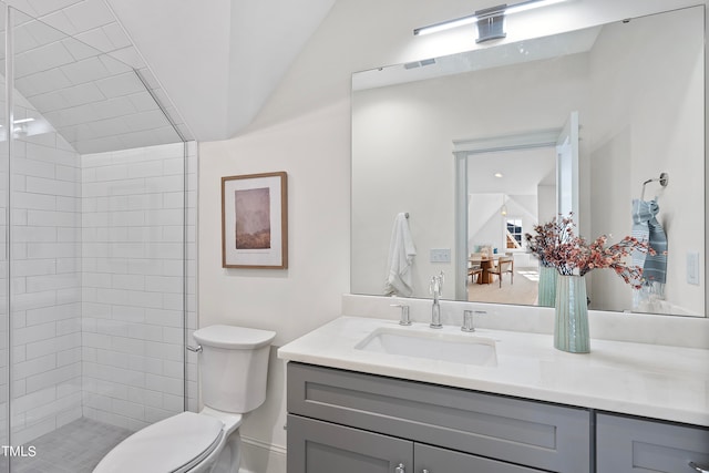 bathroom with a shower, vanity, vaulted ceiling, and toilet