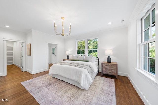 bedroom featuring dark hardwood / wood-style floors, ornamental molding, and an inviting chandelier