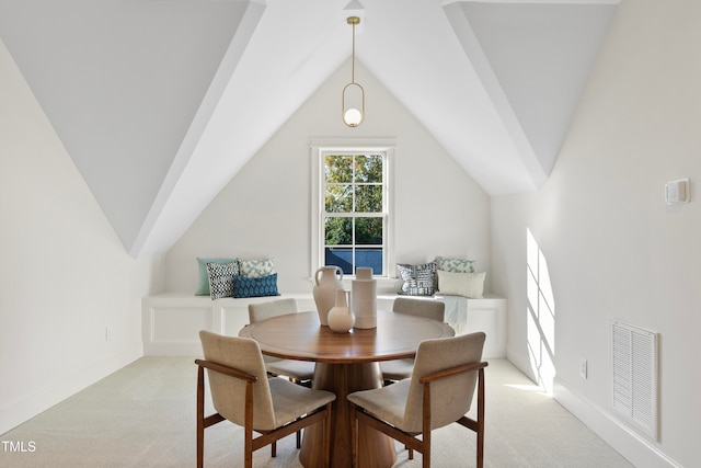 dining room with light colored carpet and vaulted ceiling