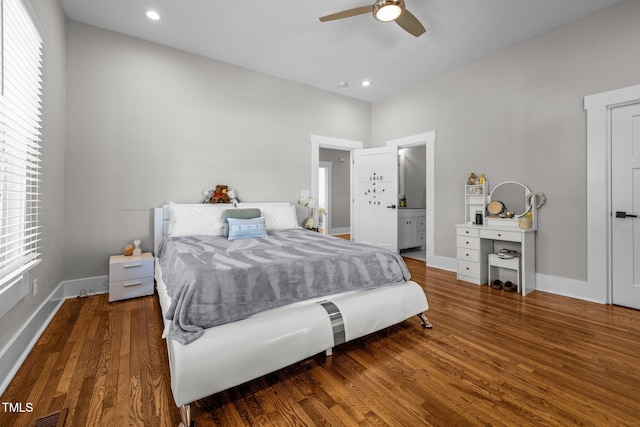 bedroom featuring ceiling fan, ensuite bath, and dark hardwood / wood-style floors