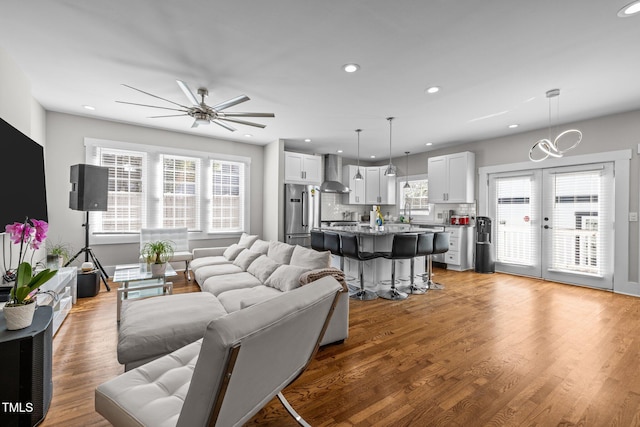 living room featuring french doors, ceiling fan, a healthy amount of sunlight, and light hardwood / wood-style flooring