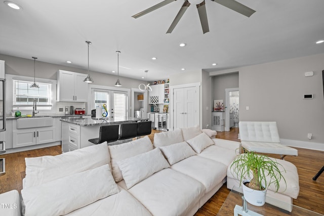 living room featuring ceiling fan, sink, and dark hardwood / wood-style floors