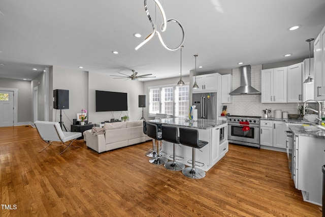 kitchen featuring a kitchen island, white cabinetry, light hardwood / wood-style floors, wall chimney exhaust hood, and premium appliances