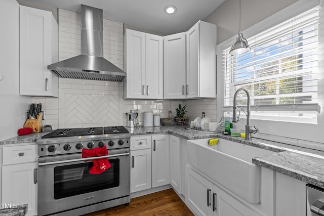 kitchen featuring wall chimney range hood, white cabinets, stainless steel appliances, and sink