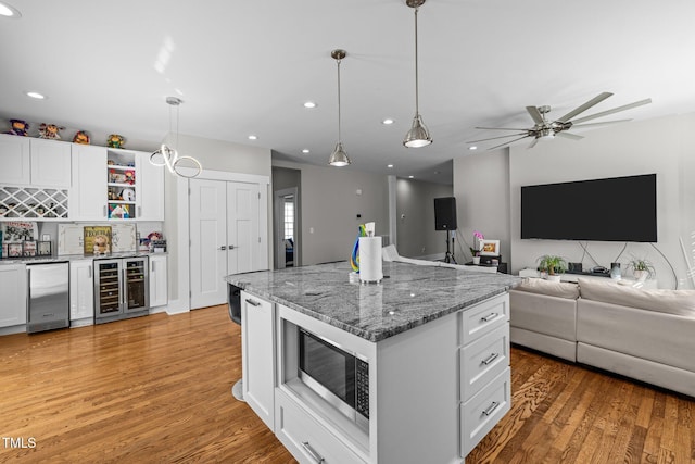 kitchen featuring wine cooler, hardwood / wood-style flooring, decorative light fixtures, and white cabinets