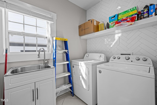 clothes washing area featuring cabinets, tile walls, light tile patterned flooring, washing machine and dryer, and sink