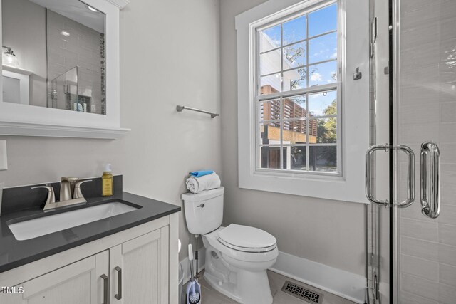 bathroom with vanity, an enclosed shower, toilet, and tile patterned floors