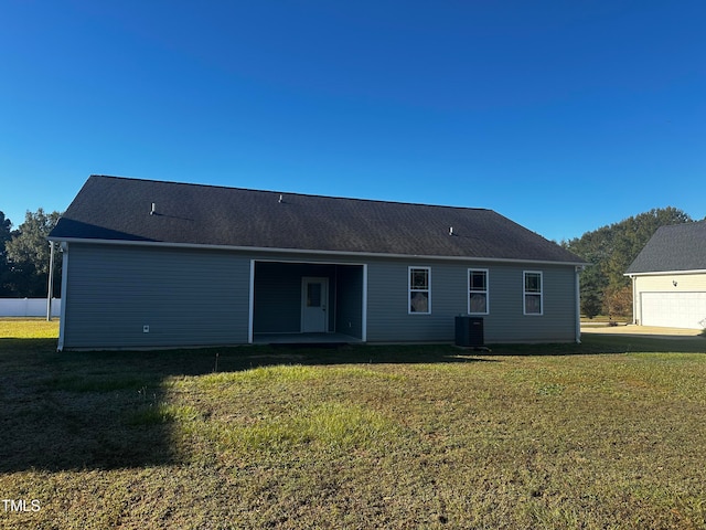 rear view of house featuring central AC unit and a lawn