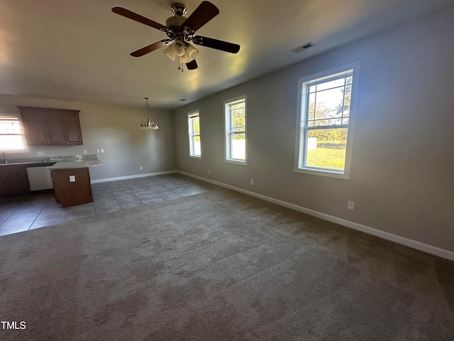 unfurnished living room featuring ceiling fan with notable chandelier and dark tile patterned flooring