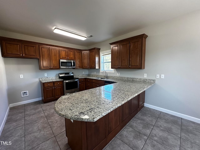 kitchen with light stone countertops, tile patterned flooring, stainless steel appliances, sink, and kitchen peninsula