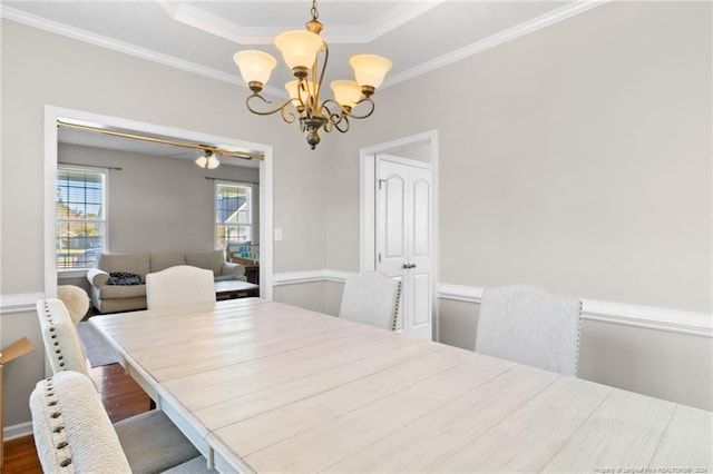 dining area with an inviting chandelier, wood-type flooring, a tray ceiling, and crown molding