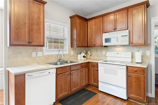 kitchen featuring white appliances, light hardwood / wood-style flooring, sink, and backsplash