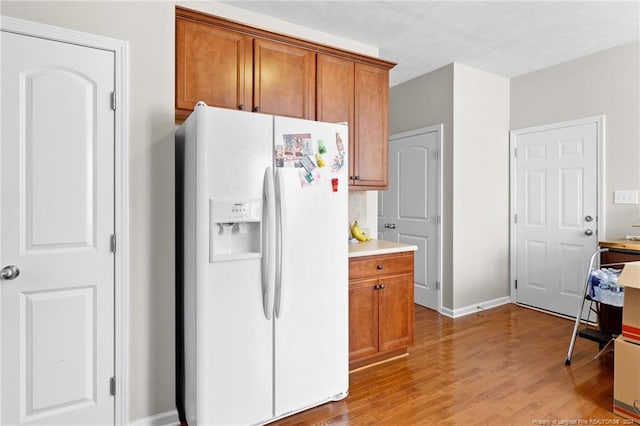 kitchen with light hardwood / wood-style floors, a textured ceiling, and white refrigerator with ice dispenser