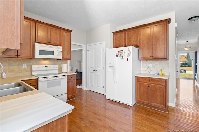 kitchen featuring hardwood / wood-style flooring, sink, tasteful backsplash, and white appliances