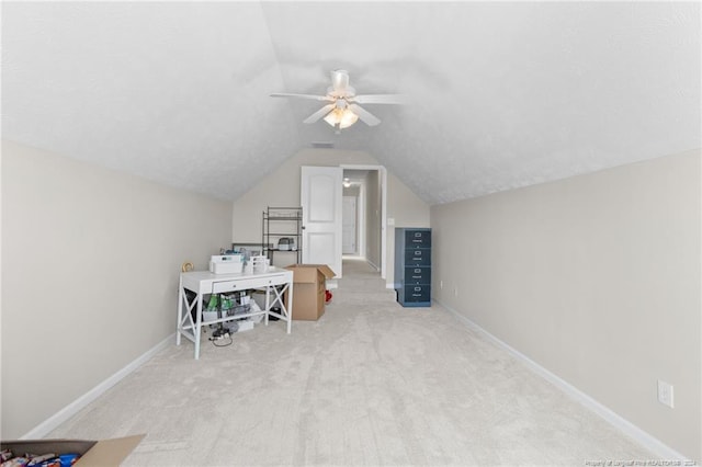 carpeted home office with ceiling fan and vaulted ceiling