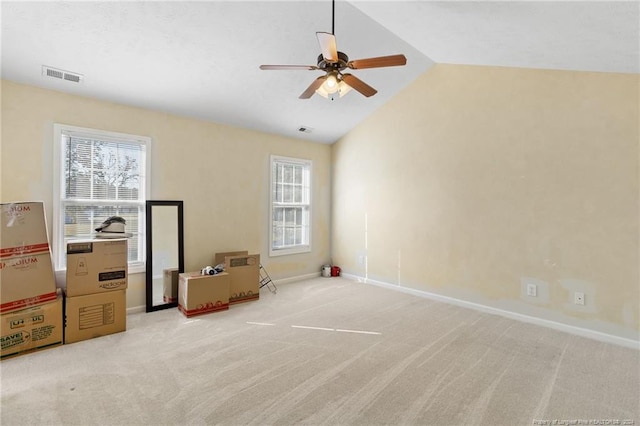 unfurnished room with ceiling fan, vaulted ceiling, a wealth of natural light, and light colored carpet