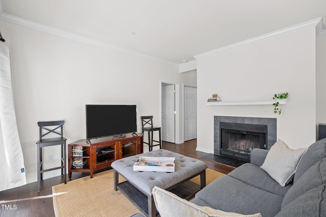 living room with a tile fireplace, crown molding, and dark hardwood / wood-style flooring