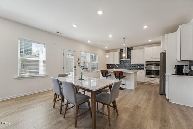 dining area featuring sink, light hardwood / wood-style floors, and a healthy amount of sunlight