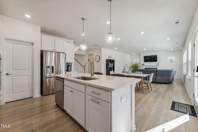 kitchen featuring white cabinetry, stainless steel appliances, sink, and a center island with sink