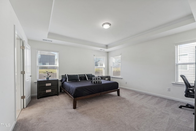 carpeted bedroom with multiple windows, ornamental molding, and a tray ceiling