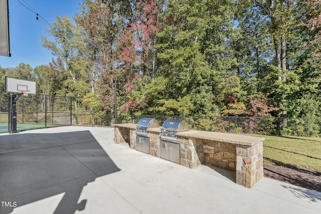 view of patio with basketball hoop, an outdoor kitchen, and area for grilling