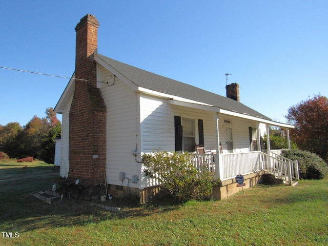 view of side of property featuring a yard and covered porch