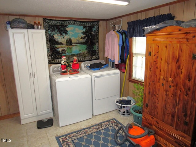 laundry area with ornamental molding, light tile patterned flooring, washing machine and dryer, and wood walls