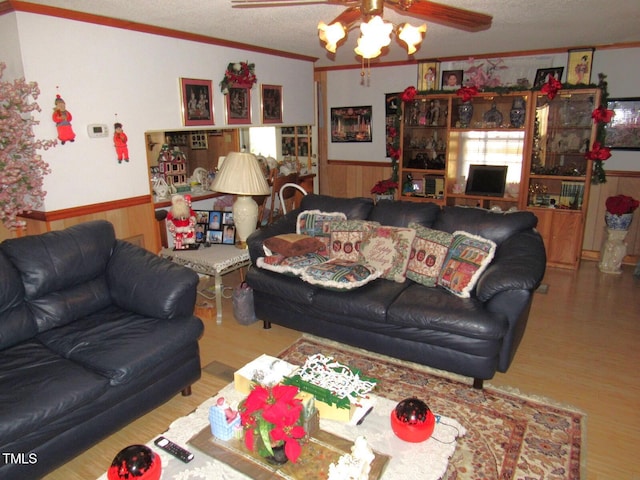 living room featuring ceiling fan, wood walls, ornamental molding, and hardwood / wood-style floors