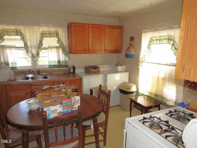 kitchen featuring independent washer and dryer, sink, and white gas range