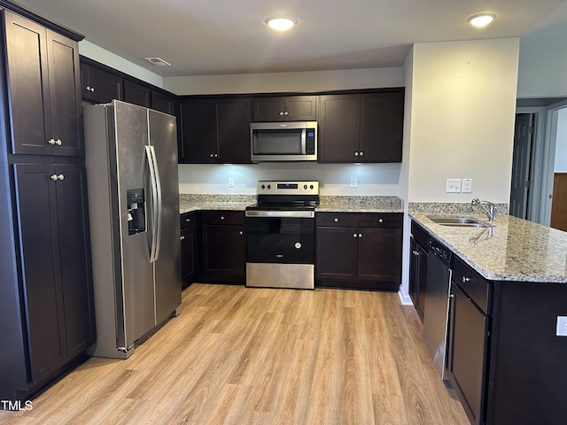 kitchen featuring sink, appliances with stainless steel finishes, kitchen peninsula, and light hardwood / wood-style floors