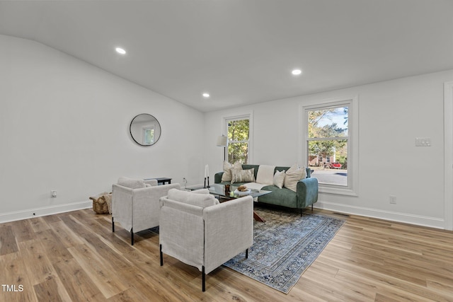 living room featuring lofted ceiling and light hardwood / wood-style flooring