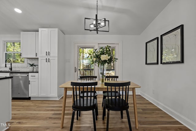 dining room featuring lofted ceiling, light hardwood / wood-style flooring, a notable chandelier, and plenty of natural light