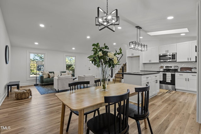 dining area with light hardwood / wood-style floors and lofted ceiling with skylight