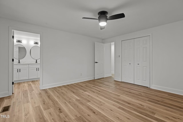 unfurnished bedroom with ensuite bath, a closet, light wood-type flooring, and ceiling fan