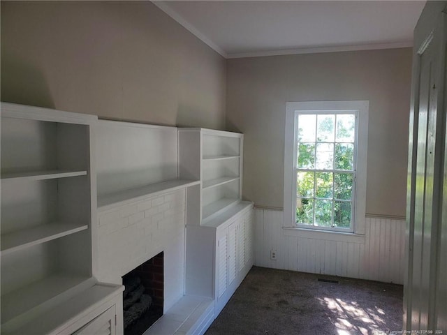 unfurnished living room featuring wooden walls, ornamental molding, a brick fireplace, and dark carpet