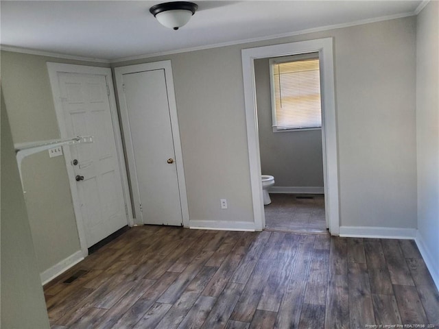 unfurnished bedroom with crown molding, dark hardwood / wood-style floors, and ensuite bath