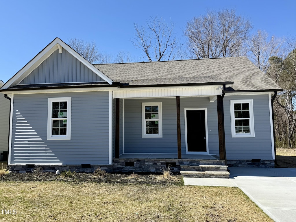 view of front facade featuring a shingled roof, crawl space, covered porch, and board and batten siding