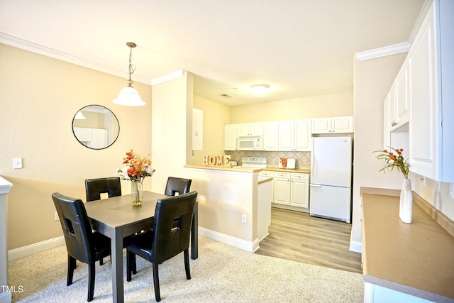 dining space featuring baseboards, light wood finished floors, and crown molding