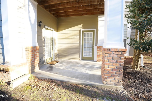 property entrance with a porch and brick siding